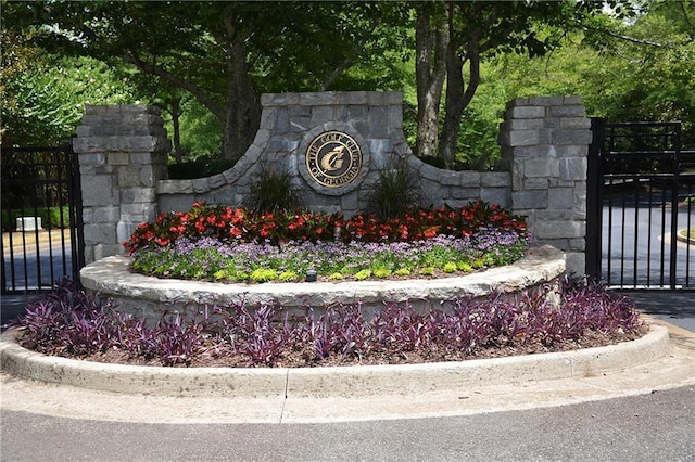 community / neighborhood sign featuring a gate and fence