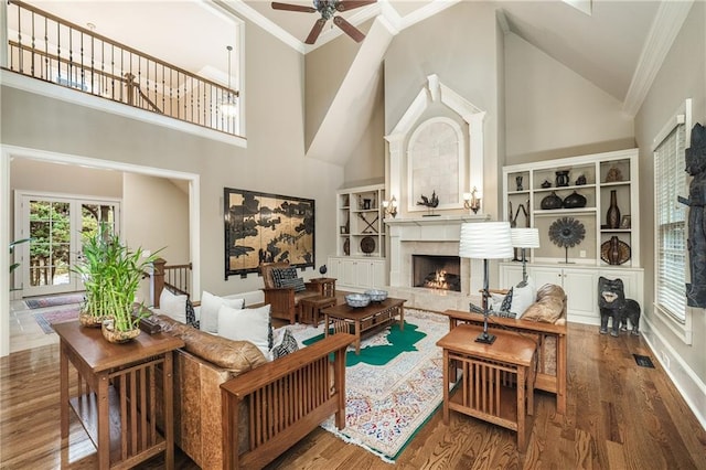 living area with ornamental molding, wood finished floors, and a high end fireplace