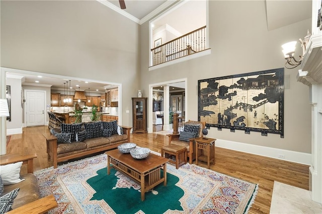 living room featuring baseboards, crown molding, light wood finished floors, and an inviting chandelier