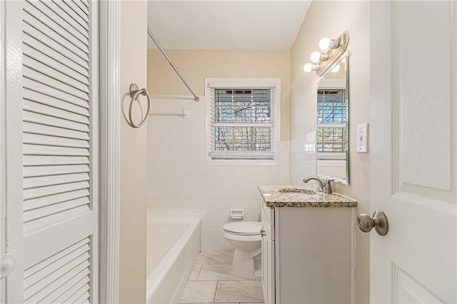 full bathroom featuring vanity, toilet, tile walls, and tub / shower combination