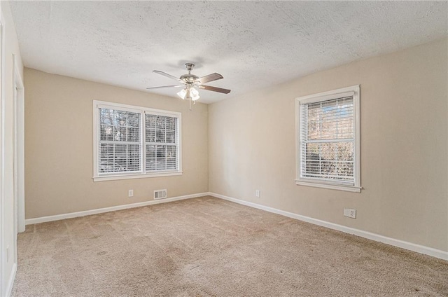 unfurnished room with ceiling fan, light colored carpet, and a textured ceiling