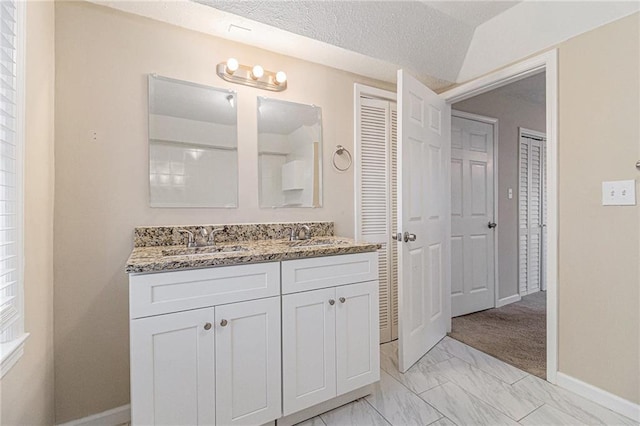 bathroom with vanity, a textured ceiling, and lofted ceiling