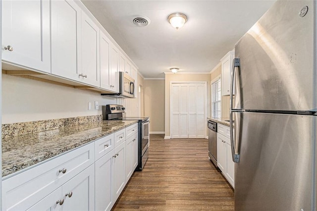 kitchen with light stone countertops, appliances with stainless steel finishes, ornamental molding, dark hardwood / wood-style floors, and white cabinetry