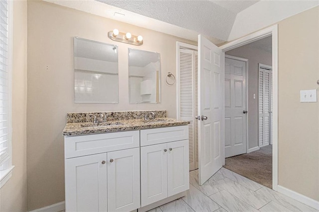 bathroom featuring vanity, a textured ceiling, and vaulted ceiling