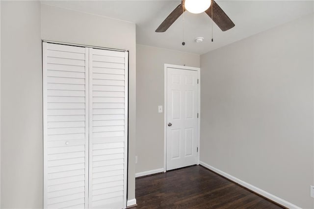 unfurnished bedroom with a ceiling fan, baseboards, dark wood finished floors, and a closet