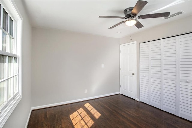 unfurnished bedroom with dark wood-style flooring, visible vents, and baseboards