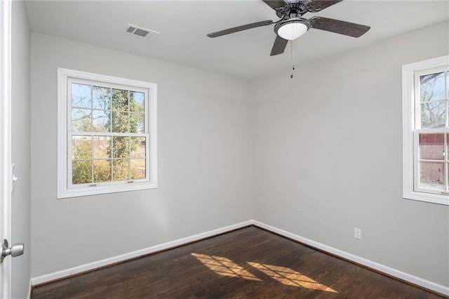 unfurnished room featuring a ceiling fan, dark wood finished floors, a wealth of natural light, and baseboards