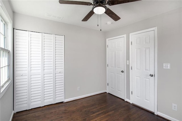 unfurnished bedroom with dark wood-style floors, ceiling fan, visible vents, and baseboards