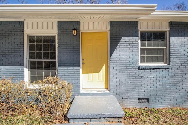 property entrance featuring brick siding and crawl space