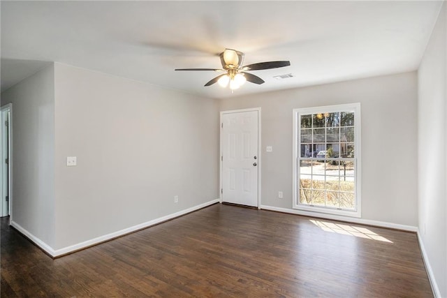 spare room featuring dark wood-style floors, visible vents, baseboards, and a ceiling fan