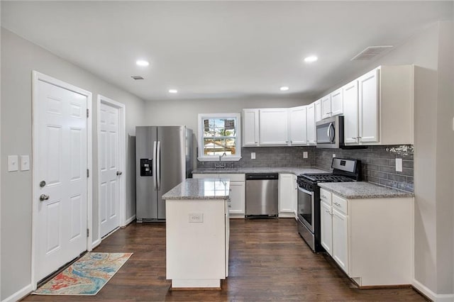 kitchen featuring dark wood finished floors, a center island, stainless steel appliances, white cabinetry, and a sink