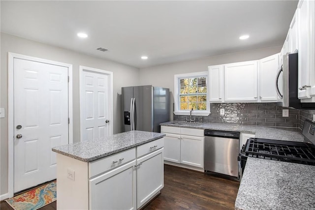 kitchen with dark wood-type flooring, a sink, white cabinetry, appliances with stainless steel finishes, and backsplash