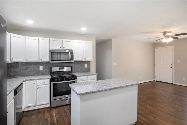 kitchen with white cabinets, a kitchen island, dark wood-type flooring, stainless steel appliances, and backsplash