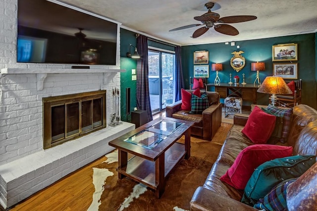 living room featuring a brick fireplace, crown molding, wood-type flooring, and ceiling fan