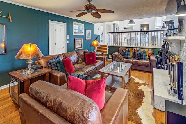 living room with ornamental molding, a brick fireplace, ceiling fan, and light hardwood / wood-style floors