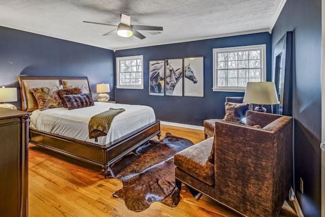 bedroom with ornamental molding, hardwood / wood-style floors, multiple windows, and a textured ceiling