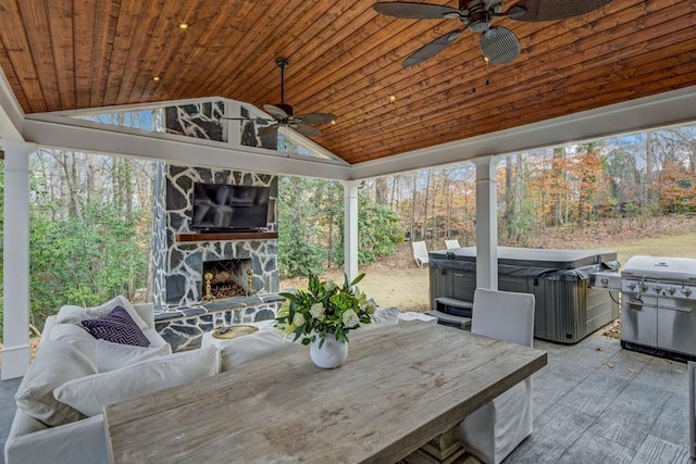 view of patio / terrace featuring a hot tub, a grill, and an outdoor stone fireplace