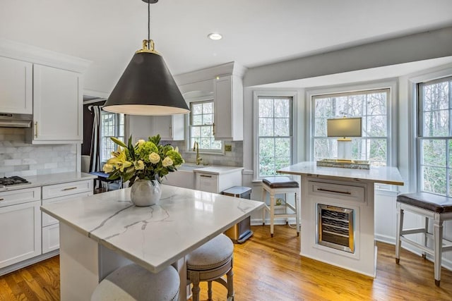 kitchen featuring pendant lighting, a center island, white cabinets, and light wood-type flooring