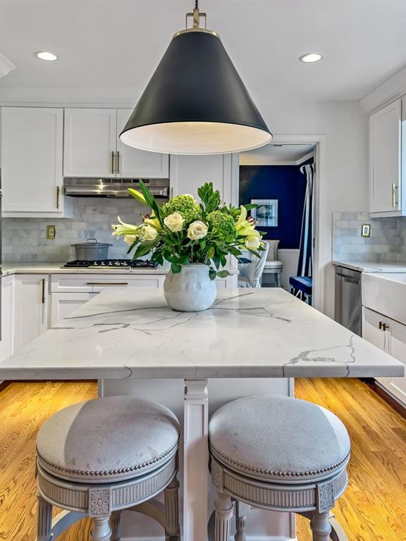 kitchen with stainless steel appliances, light stone counters, white cabinets, and a kitchen bar