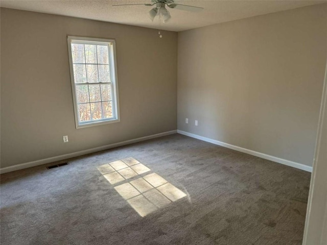 carpeted spare room featuring ceiling fan and a textured ceiling