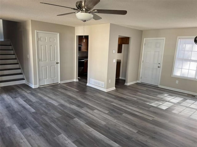 unfurnished living room featuring ceiling fan, dark hardwood / wood-style floors, and a textured ceiling