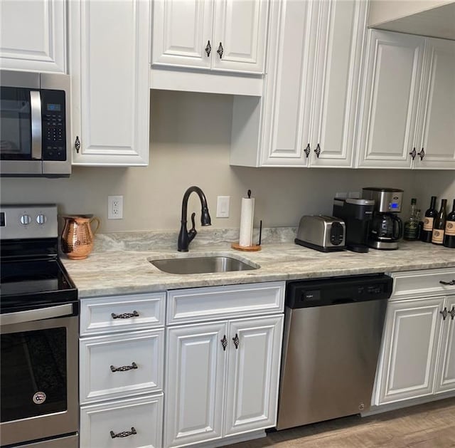 kitchen featuring appliances with stainless steel finishes, white cabinetry, and sink