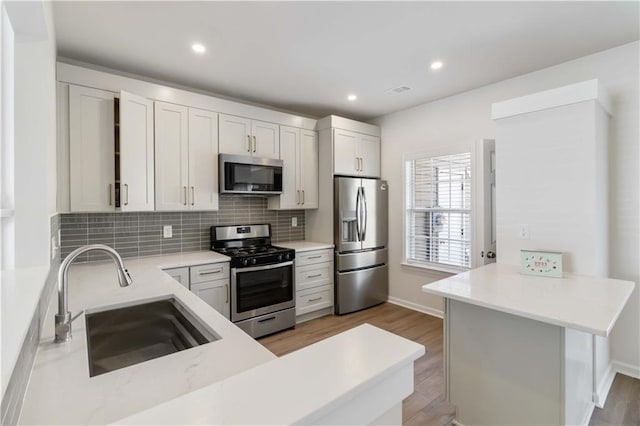 13300 Morris Rd Unit 76, Alpharetta, GA 30004 - kitchen with backsplash, dark wood-style flooring, appliances with stainless steel finishes, a sink, and white cabinets