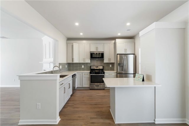13300 Morris Rd Unit 76, Alpharetta, GA 30004 - kitchen with a peninsula, wood finished floors, tasteful backsplash, a sink, and appliances with stainless steel finishes
