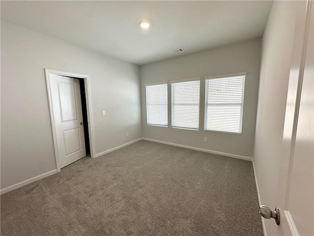 spare room featuring visible vents, carpet floors, and baseboards