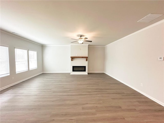 unfurnished living room featuring wood finished floors, visible vents, a fireplace, ornamental molding, and ceiling fan