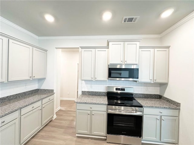 kitchen with visible vents, appliances with stainless steel finishes, crown molding, light wood finished floors, and decorative backsplash