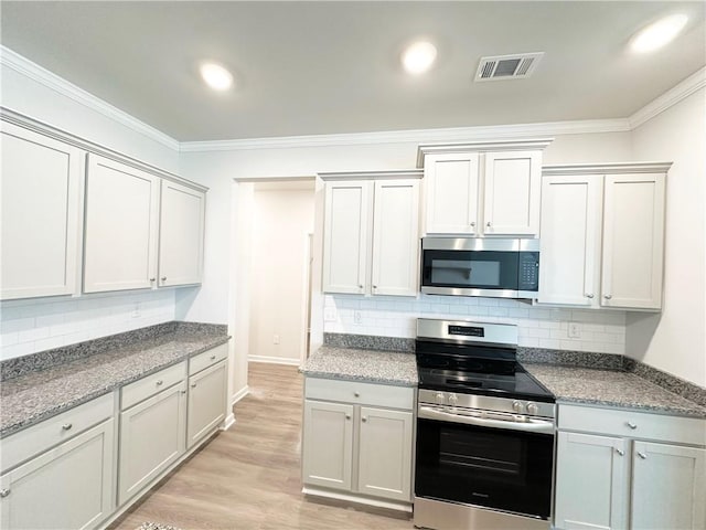 kitchen with visible vents, stainless steel appliances, light wood-style floors, and ornamental molding