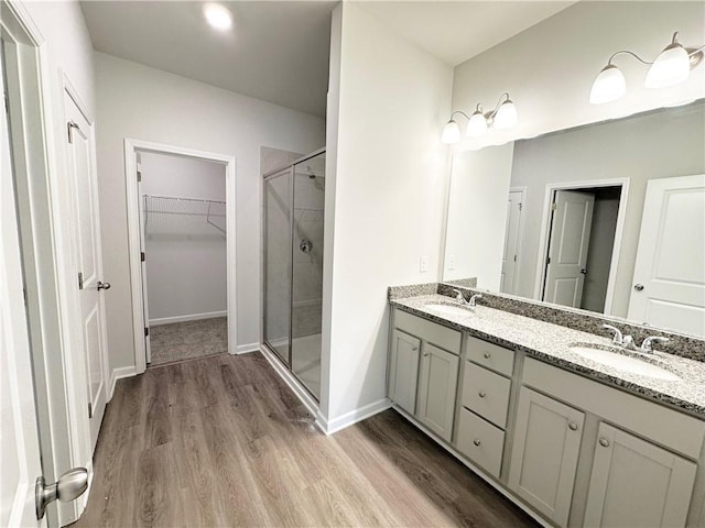 full bath with a sink, wood finished floors, and a stall shower