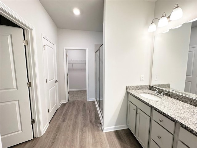 full bath featuring vanity, wood finished floors, a stall shower, and baseboards