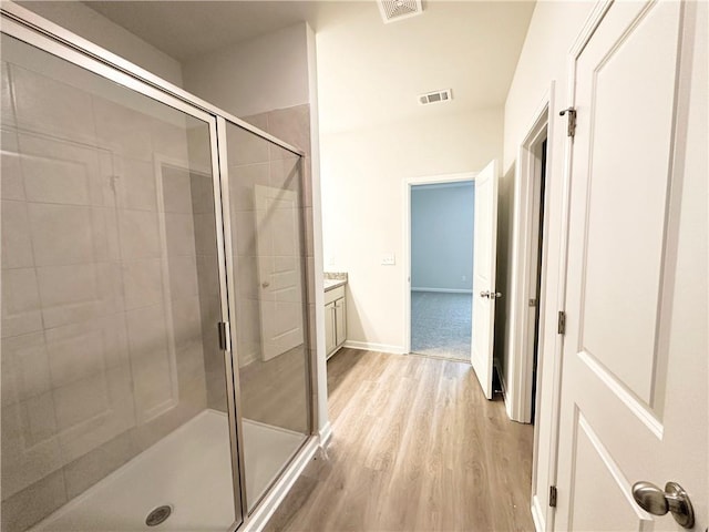 bathroom with visible vents, wood finished floors, a stall shower, and vanity