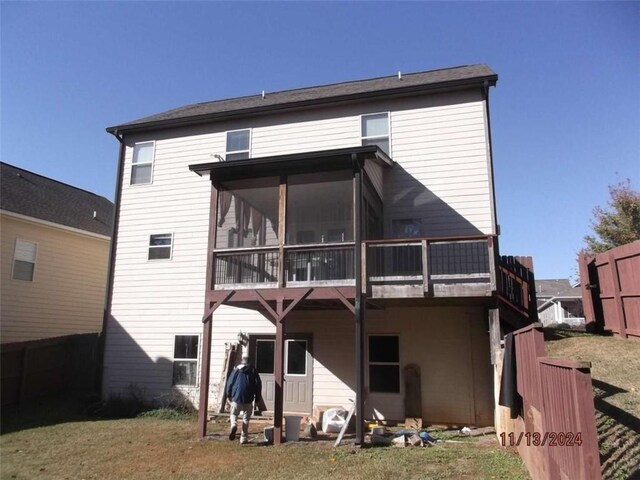 back of house featuring a lawn and a sunroom