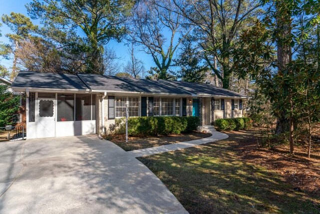 ranch-style house featuring a sunroom and a front yard