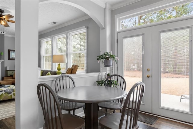 dining area with a textured ceiling, wood finished floors, visible vents, french doors, and ornamental molding