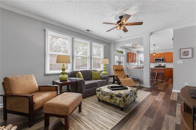 living room featuring dark wood-style floors, visible vents, ornamental molding, a textured ceiling, and baseboards