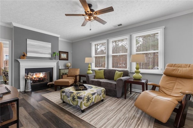 living room with a healthy amount of sunlight, crown molding, visible vents, and wood finished floors