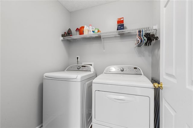 clothes washing area with washer and dryer, laundry area, and a textured ceiling