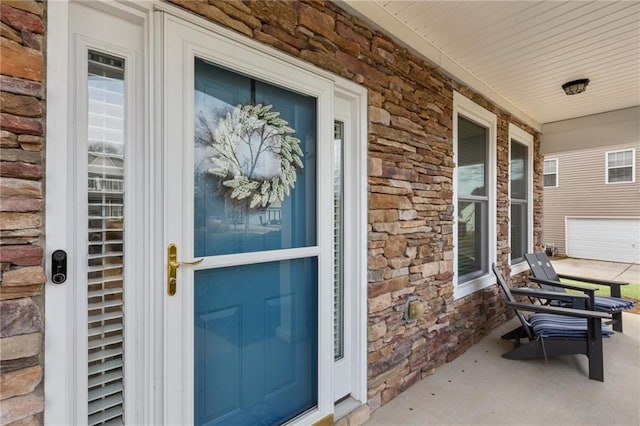 entrance to property featuring stone siding and a porch