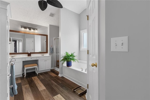 full bath with visible vents, a stall shower, vanity, wood finished floors, and a bath