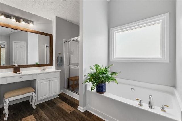 full bath with a shower stall, a textured ceiling, wood finished floors, and vanity