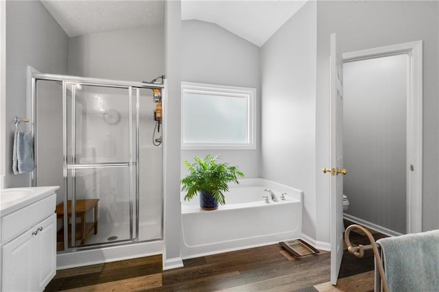 bathroom featuring a stall shower, a garden tub, lofted ceiling, and wood finished floors