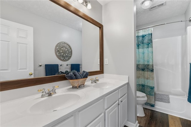 bathroom with toilet, a textured ceiling, visible vents, and a sink