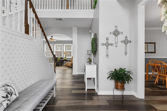 foyer featuring stairway, visible vents, arched walkways, and dark wood-style flooring