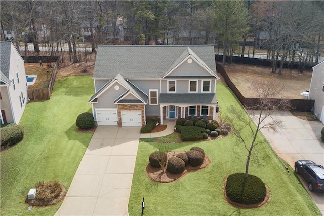 traditional-style home featuring a garage, a shingled roof, concrete driveway, and a front yard