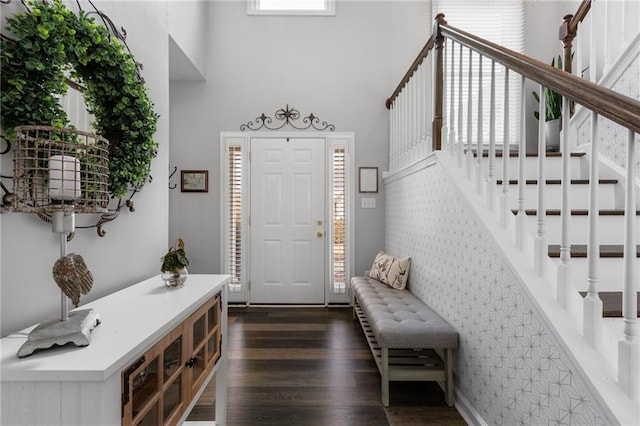 foyer entrance with a high ceiling, stairway, and dark wood-type flooring