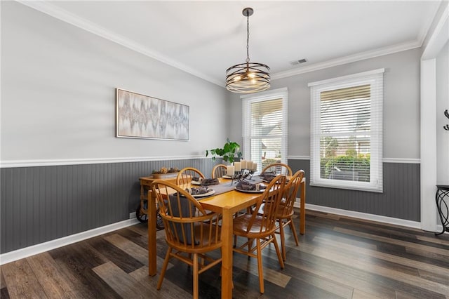 dining room featuring a wainscoted wall, visible vents, ornamental molding, wood finished floors, and baseboards